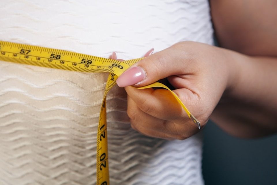 Close-up of a woman measuring her chest with a tape measure.